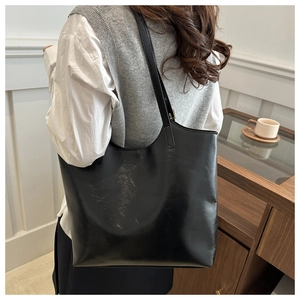Detailed close-up of glossy black leather tote bag with soft texture and premium shine