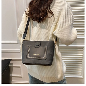 Rear view of model wearing black leather bucket bag with wide strap and gold hardware