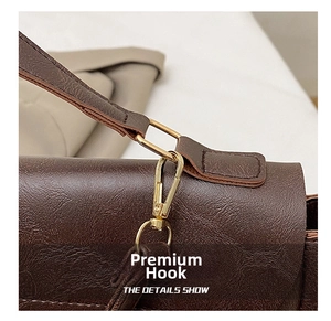 Close-up of premium gold-toned metal hook and textured dark brown leather on tote bag