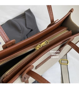 Détail de la fermeture éclair en métal sur un sac en toile avec garniture en cuir marron