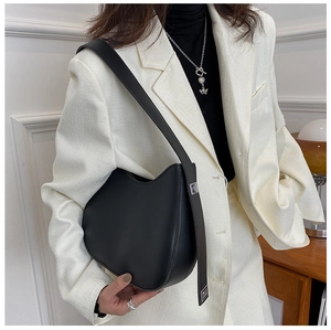 Detail of black leather crescent underarm bag with silver buckle and wide strap on model