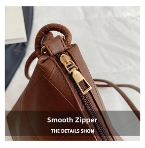 Close-up of golden metal zipper and stitching on a dark brown leather tote bag
