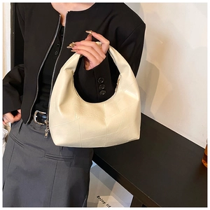 Close-up of minimalist off-white pleated hobo bag with geometric stitching details