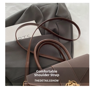Detail of a brown leather bag showing the golden A-shaped metal clasp and textured strap
