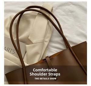 Detailed close-up of dark brown leather tote bag straps with reinforced stitching