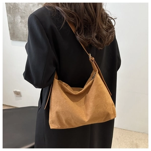 Caramel suede hobo bag shown on shoulder with minimalist styling and natural texture