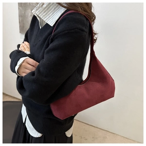 Side view of a vintage burgundy suede hobo bag worn with a black sweater for autumn style