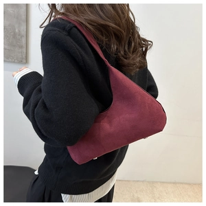Side view of a burgundy matte suede shoulder bag with protective metal bottom studs