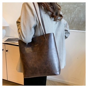 Detail of deep brown tote bag featuring retro leather texture and elegant gold lettering