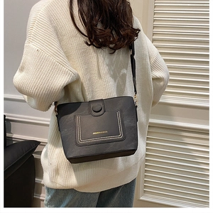 Detail of black bucket bag with gold studs and FASHION & BAGS logo on a white sweater