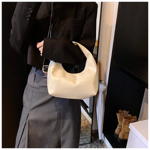 Close-up of cream patchwork cloud bag paired with chic grey pleated skirt and blazer