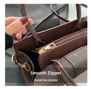 Detail view of smooth light gold metal zipper on brown textured PU leather handbag