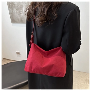 Close-up of red suede shoulder bag showing soft texture and leather strap detail
