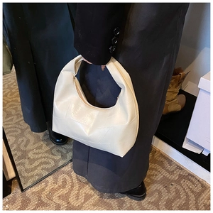 Detail of cream pleated hobo bag with geometric patchwork and glossy finish
