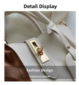 Macro view of white lychee leather texture and golden metal twist-lock on stylish handbag