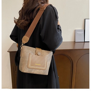 Close-up of a vintage tan bucket bag with wide fabric strap and contrast stitching details
