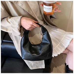 Detail of minimalist black moon bag with premium leather texture held by a fashion model