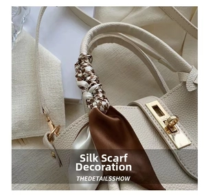Detail of cream pebbled leather bucket bag with gold lock and checkered silk scarf handle