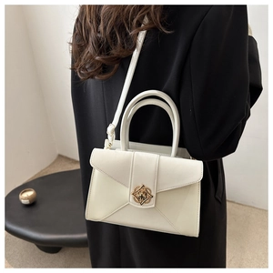 Detailed side view of white structured handbag with golden circular lock on dark blazer