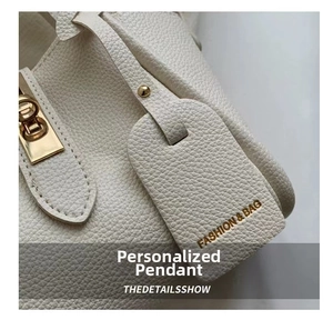 Detail of white lychee grain leather bag with gold buckle and fashion bag charm