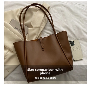 Deep brown tote bag detail showing size comparison with smartphone and strap texture