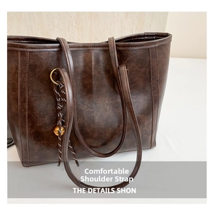 Close-up of the vintage leather texture and woven charm detail on this brown tote bag