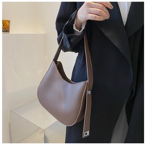 Brown hobo shoulder bag with matte leather texture shown on a black trench coat