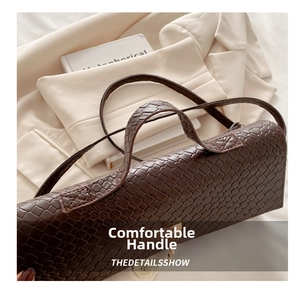 Detail of the vintage embossed texture and gold metal buckle on a brown baguette bag