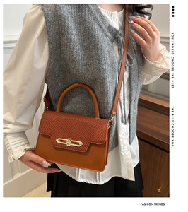Detail of a brown textured box bag featuring woven patterns and a golden buckle lock