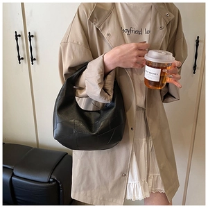 Detail of minimalist black leather hobo bag with pleated texture and soft lychee grain