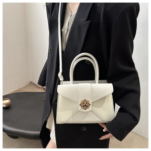 Detail of cream white minimalist handbag with gold metal clasp and adjustable strap