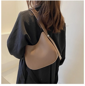 Detail of a brown crescent-shaped underarm bag with an adjustable wide shoulder strap