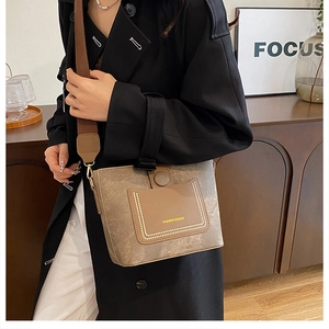 Detail of retro brown bucket bag with contrasting front pocket and gold stud accents