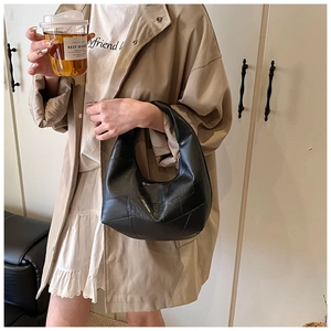 Minimalist black crescent bag with patchwork leather texture shown in a lifestyle street style