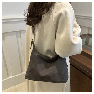 Detail of grey suede shoulder bag texture and metal buckle on long strap
