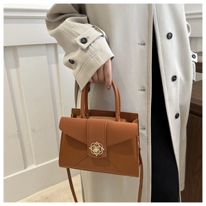 Close-up of caramel leather handbag with vintage gold floral buckle and envelope fold