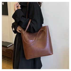 Detailed view of brown leather tote bag with large front pockets and long shoulder straps