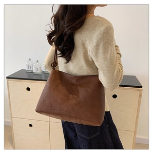 Detailed patchwork texture of brown leather tote bag worn by a model in casual setting