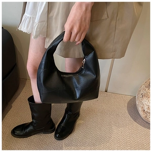Detail of minimalist black pleated hobo bag with textured stitching and metal zipper