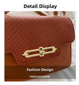 Macro shot of the brown textured leather and gold metal chain lock on a crossbody bag