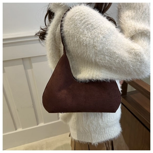Detail of a brown matte suede underarm bag shown with metal bottom studs and soft texture