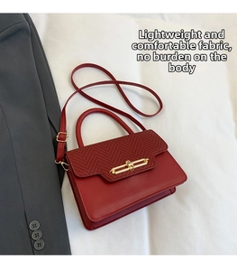 Detail of red leather crossbody bag with textured fabric flap and gold metal clasp lock