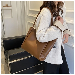 Brown leather tote bag worn by model in a modern interior setting for casual style