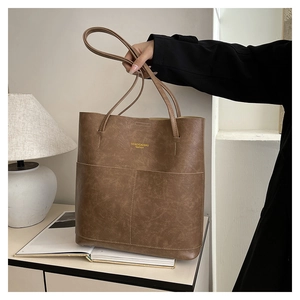 Detail of a brown oil wax leather tote bag with elegant gold embossed branding logo