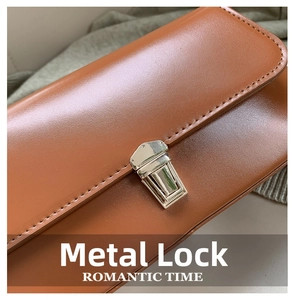 Détail macro du fermoir en métal argenté sur un sac en cuir marron avec coutures précises