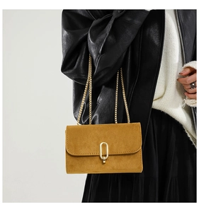 Détail du petit sac carré en daim ambre avec fermoir doré et bandoulière en chaîne