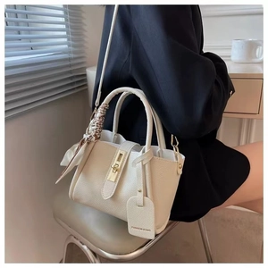 Close-up of off-white lychee leather bucket bag with gold hardware and silk scarf detail