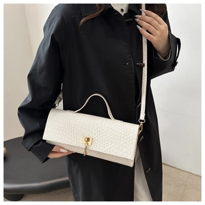 Detail of white woven texture leather bag with gold clasp shown on a black coat