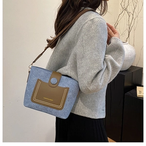 Detail of light blue denim and brown leather bucket bag shown in a modern interior setting