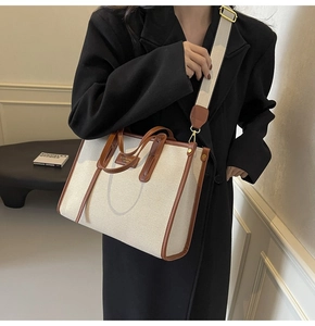 Détail du sac cabas en toile avec poignées en cuir marron et bandoulière tissée